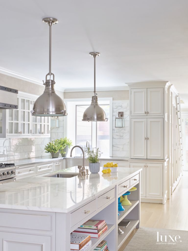 completely white kitchen with chrome pendant lighting and book shelf